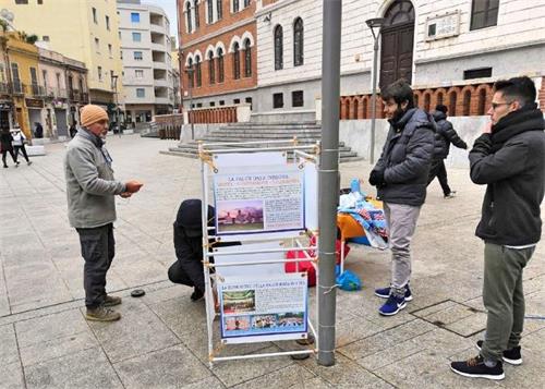 '图1：二零一九年一月十三日，意大利撒丁岛的法轮功学员在卡利亚里市（Cagliari）设立真相点传播法轮功的真相。不少路人驻足了解真相。'
