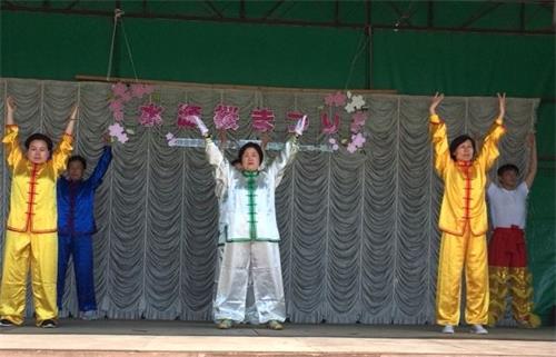 '图5：法轮功学员在丰田市水源公园樱花节的舞台上进行法轮功的功法展示'