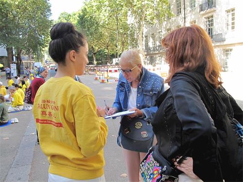 '图19：西班牙女学员正在向两位西班牙游客讲真相'