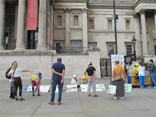 '图1～3：二零二零年八月二十二日，英国法轮功学员在伦敦特拉法加广场（Trafalgar Square）北平台开展讲真相反迫害活动，民众驻足观看、了解真相，签名支持制止迫害。'
