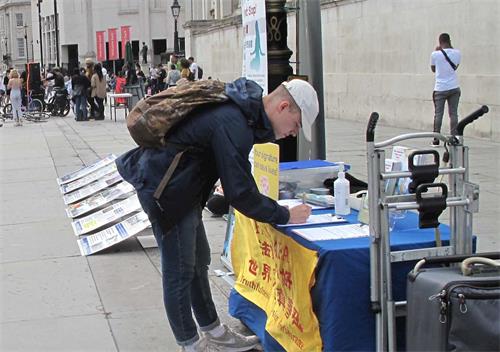 '图9：二零二零年八月二十二日，在特拉法加广场，在伦敦学医的大学生帕特里克（Patrick）签名支持制止迫害。'
