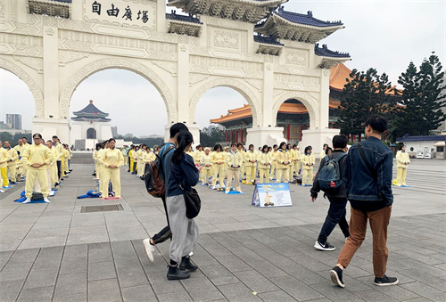 '图1～2：被疫情笼罩的台北市，法轮功学员集体炼功散发的祥和能量场吸引前来自由广场的游客驻足拍照，拍下这珍贵的场面。'