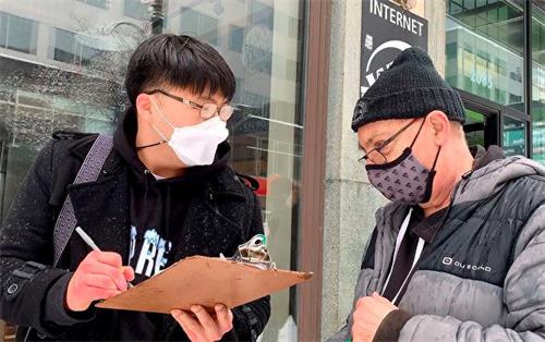 '图9：韩国青年（左）非常赞同游行传递的信息，在呼吁制裁中共的征签板上签字。'