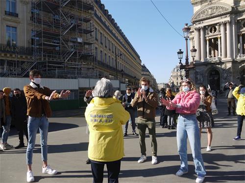 '图7：几个年轻人在巴黎歌剧院广场学炼法轮功'