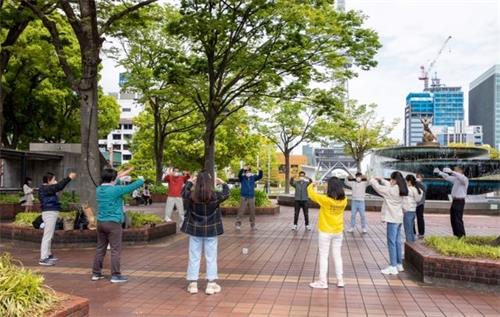 '图1：法轮功学员在日本名古屋市（Nagoya-City）中心的繁华地段炼功，向民众介绍功法。'