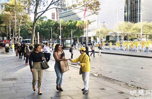 图1～2：匆匆赶着上班的主流人士被一片祥和的场面吸引，悉尼法轮功学员正迎着朝霞集体晨炼