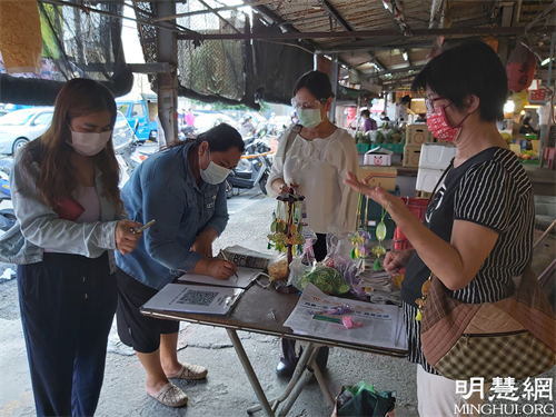 图1：法轮功学员在云林虎尾黄昏市场讲真相发送莲花书签及真相资料。