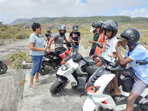 '图：二零二一年三月二十八日，在瓜德罗普南部小岛德斯拉德（la Désirade），法轮功学员（左一）向一群骑摩托车的人讲法轮功真相。'
