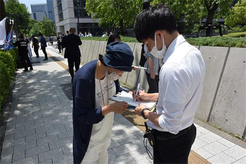 图5：川村先生在征签表格上签名支持法轮功学员反迫害活动