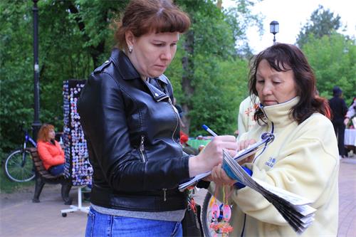 '图2～5：法轮功学员们向来参加安加尔斯克市城市日庆祝活动的人们讲述法轮功的真相，并征集签名。了解真相的人们纷纷在征签表上签名。'